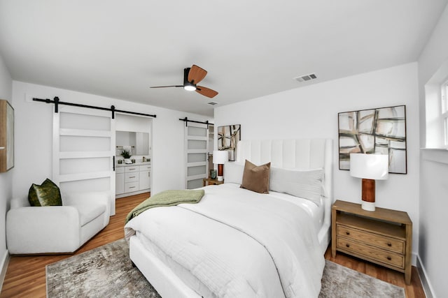 6249 Locke Ln, Houston, TX 77057 - bedroom featuring a barn door, wood finished floors, baseboards, and a ceiling fan