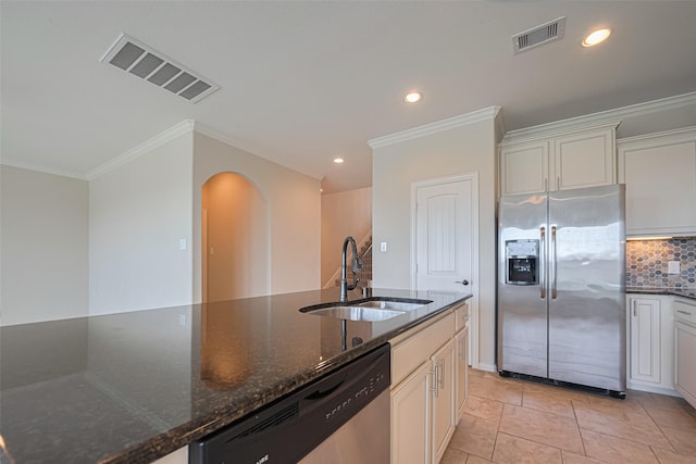 20619 Cactus Lake Ln, Richmond, TX 77407 - kitchen featuring appliances with stainless steel finishes, a sink, arched walkways, dark stone countertops, and decorative backsplash
