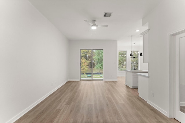 1009 Spokane River Rd, Conroe, TX 77316 - unfurnished living room with light wood finished floors, a sink, a ceiling fan, and baseboards
