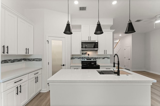 1009 Spokane River Rd, Conroe, TX 77316 - kitchen with appliances with stainless steel finishes, a sink, decorative backsplash, light wood finished floors, and recessed lighting