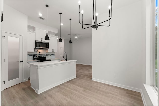 1009 Spokane River Rd, Conroe, TX 77316 - kitchen featuring appliances with stainless steel finishes, a sink, a chandelier, a kitchen island with sink, and light wood finished floors