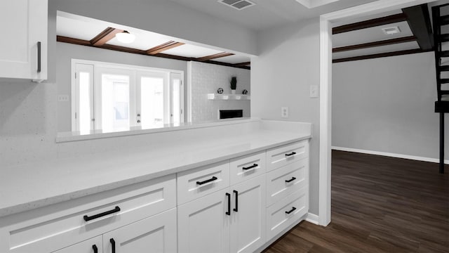 2814 Cambridge Ln, Missouri City, TX 77459 - kitchen with white cabinets, dark wood-type flooring, a brick fireplace, light stone countertops, and baseboards