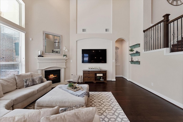 515 Arbor Point Ct, Pinehurst, TX 77362 - living room with plenty of natural light, a towering ceiling, dark wood-style floors, a lit fireplace, and baseboards