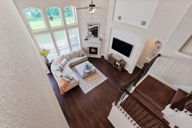 515 Arbor Point Ct, Pinehurst, TX 77362 - living area with a lit fireplace, a towering ceiling, ceiling fan, wood finished floors, and arched walkways