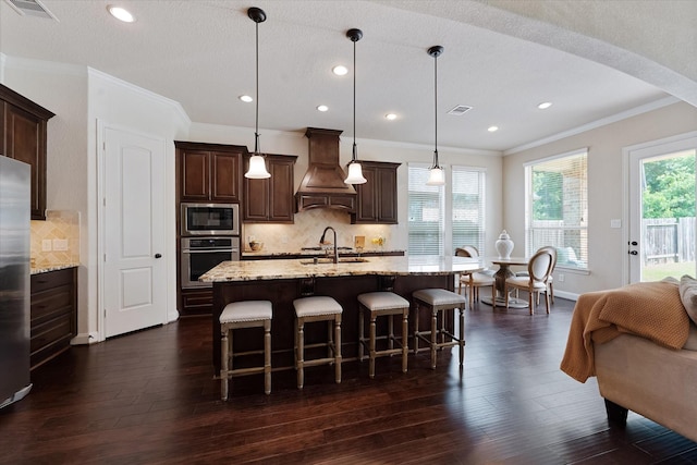 515 Arbor Point Ct, Pinehurst, TX 77362 - kitchen with stainless steel appliances, custom exhaust hood, ornamental molding, arched walkways, and dark wood-style floors