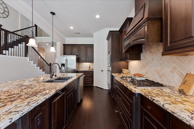 515 Arbor Point Ct, Pinehurst, TX 77362 - kitchen featuring stainless steel appliances, a sink, light stone countertops, dark brown cabinetry, and crown molding