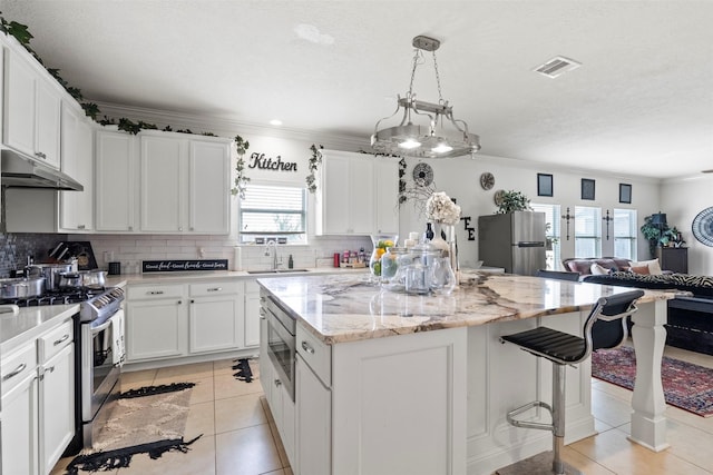 6407 Hillock Ln, Pearland, TX 77584 - kitchen featuring appliances with stainless steel finishes, under cabinet range hood, a sink, a kitchen island, and open floor plan