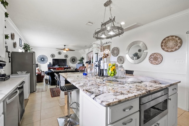 6407 Hillock Ln, Pearland, TX 77584 - kitchen featuring appliances with stainless steel finishes, a center island, crown molding, light tile patterned floors, and ceiling fan