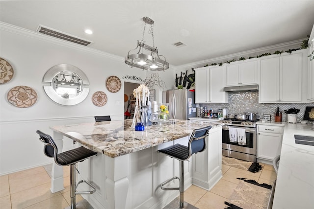 6407 Hillock Ln, Pearland, TX 77584 - kitchen with stainless steel appliances, crown molding, light tile patterned flooring, a kitchen island, and light stone counters