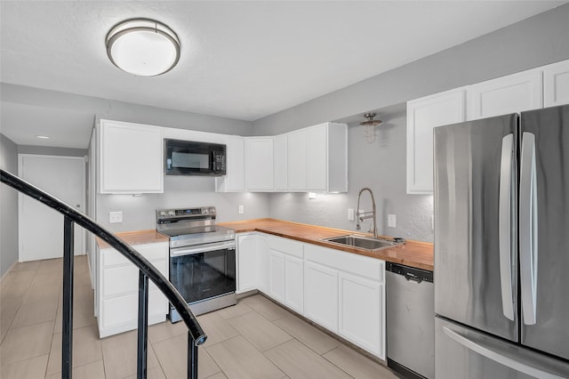 12900 Walden Rd Unit 406D, Montgomery, TX 77356 - kitchen featuring appliances with stainless steel finishes, butcher block countertops, a sink, and white cabinetry