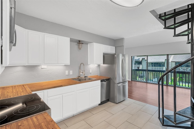 12900 Walden Rd Unit 406D, Montgomery, TX 77356 - kitchen featuring a sink, butcher block counters, appliances with stainless steel finishes, and white cabinetry