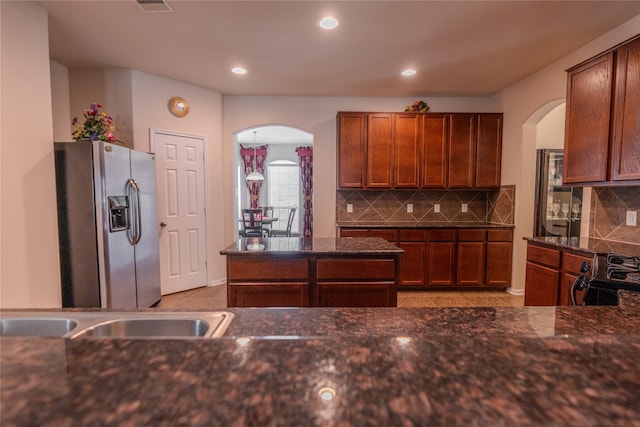 3418 Quarry Place Ln, Katy, TX 77493 - kitchen with stainless steel fridge with ice dispenser, arched walkways, tasteful backsplash, recessed lighting, and brown cabinets