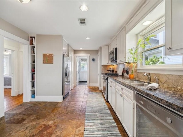 1427 Hall Pl, Houston, TX 77008 - kitchen featuring appliances with stainless steel finishes, a sink, backsplash, white cabinetry, and baseboards