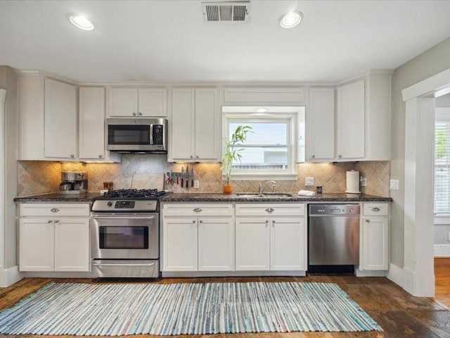 1427 Hall Pl, Houston, TX 77008 - kitchen with appliances with stainless steel finishes, a sink, white cabinets, backsplash, and baseboards