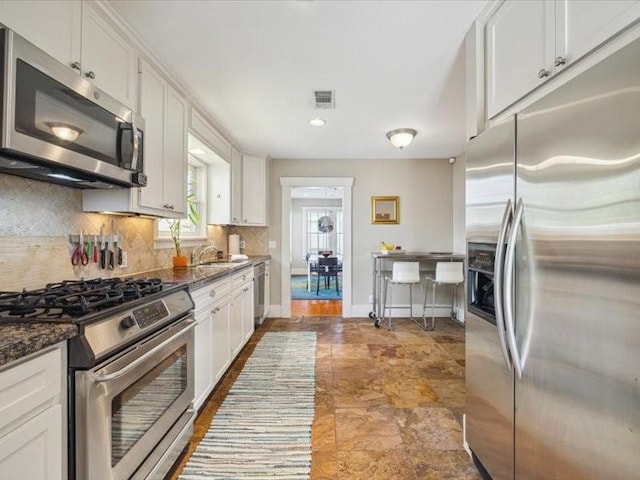1427 Hall Pl, Houston, TX 77008 - kitchen with stainless steel appliances, tasteful backsplash, white cabinets, a sink, and recessed lighting