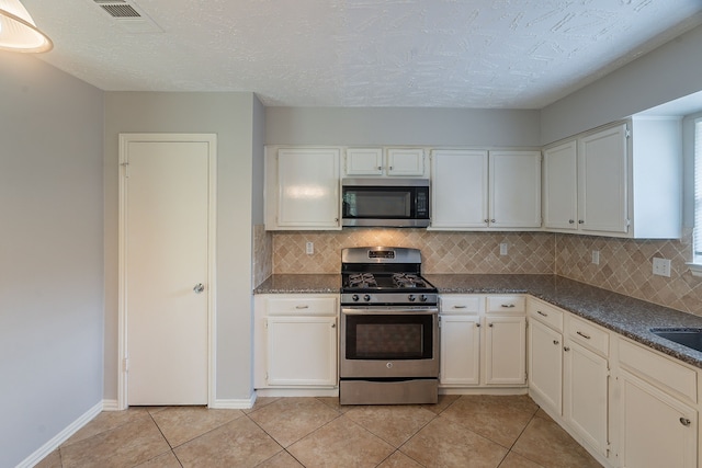 11714 Welshpool Glen Dr, Houston, TX 77066 - kitchen with stainless steel appliances, backsplash, light tile patterned flooring, white cabinetry, and baseboards