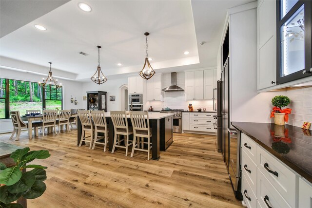 151 Alamo Dr, Huntsville, TX 77340 - kitchen with wall chimney exhaust hood, tasteful backsplash, a kitchen breakfast bar, recessed lighting, and stainless steel appliances