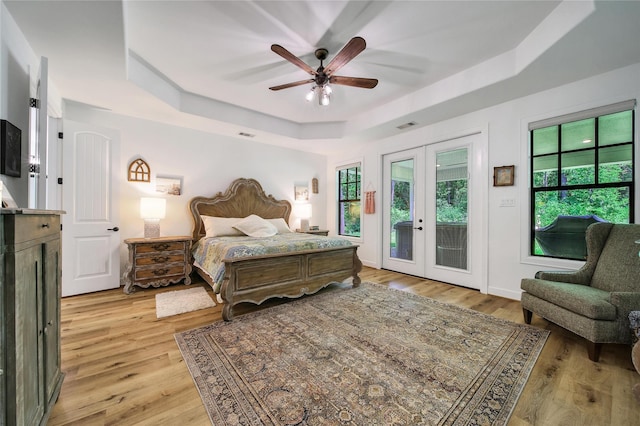 151 Alamo Dr, Huntsville, TX 77340 - bedroom featuring a raised ceiling, access to exterior, light wood-style flooring, french doors, and a ceiling fan