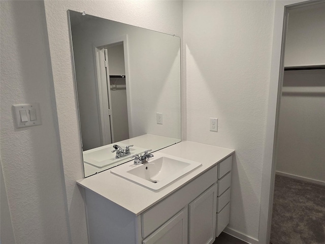 10823 Red Orchid Dr, Houston, TX 77016 - bathroom featuring vanity, a spacious closet, and a textured wall