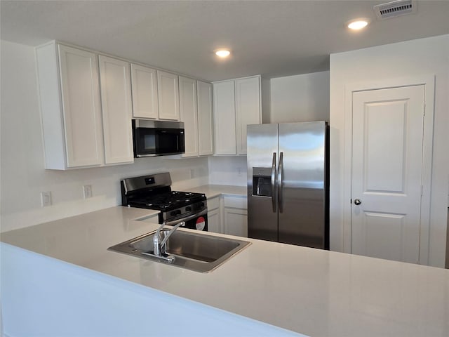 10823 Red Orchid Dr, Houston, TX 77016 - kitchen featuring stainless steel appliances, a sink, light countertops, white cabinets, and recessed lighting
