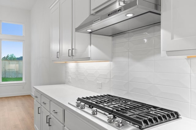 26915 Longwood Ledge Dr, Spring, TX 77389 - kitchen featuring exhaust hood, stainless steel gas stovetop, light countertops, white cabinets, and decorative backsplash