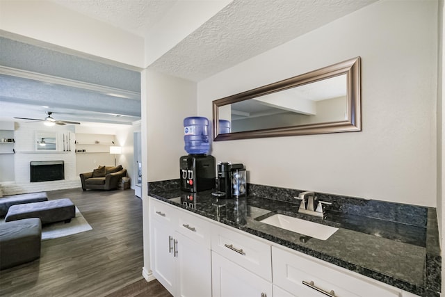 16011 Southampton Dr, Spring, TX 77379 - indoor wet bar with a textured ceiling, dark wood-type flooring, a ceiling fan, and a brick fireplace