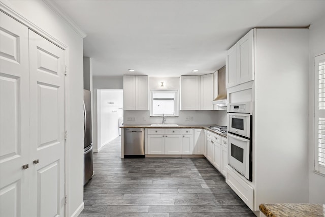 3831 Linklea Dr, Houston, TX 77025 - kitchen featuring stainless steel appliances, a sink, dark wood finished floors, recessed lighting, and white cabinetry