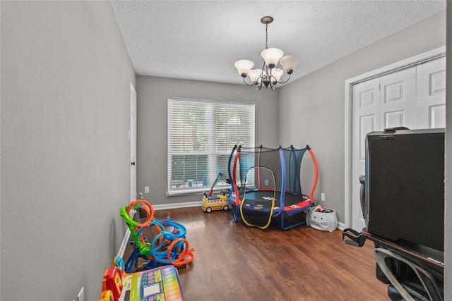 8610 Venture Ln, La Porte, TX 77571 - game room with a chandelier, a textured ceiling, wood finished floors, and baseboards