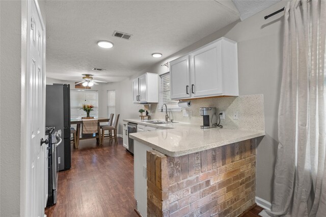 8610 Venture Ln, La Porte, TX 77571 - kitchen with a sink, a peninsula, white cabinets, light countertops, and dark wood finished floors