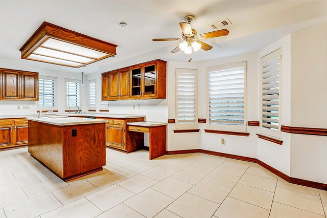 6225 Morton Rd, Katy, TX 77493 - kitchen featuring brown cabinetry, light countertops, a ceiling fan, glass insert cabinets, and a kitchen island