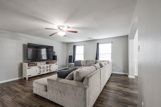 17307 Morning Star Ave, Crosby, TX 77532 - living room featuring ceiling fan, arched walkways, dark wood-style flooring, baseboards, and a textured ceiling