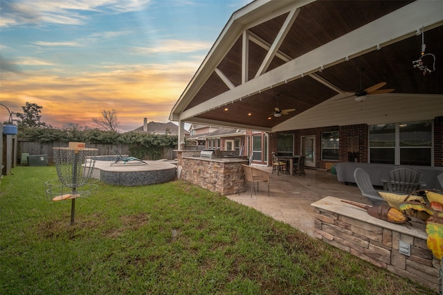 2718 Van Gogh Ln, Missouri City, TX 77459 - yard at dusk featuring a ceiling fan, an outdoor kitchen, exterior bar, a patio area, and a hot tub
