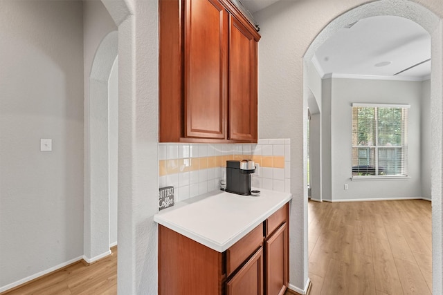 6219 Royal Hollow Ln, Katy, TX 77450 - kitchen featuring light wood-style floors, decorative backsplash, arched walkways, light countertops, and ornamental molding