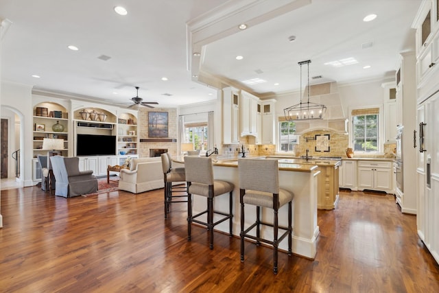 5626 Willers Way, Houston, TX 77056 - kitchen with ornamental molding, a ceiling fan, a large fireplace, dark wood-type flooring, and glass insert cabinets