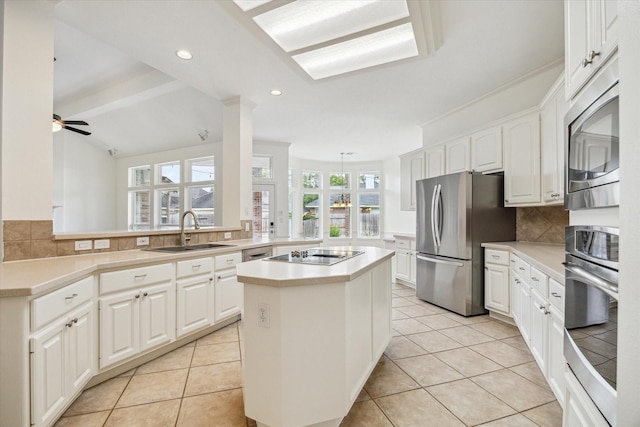12210 Pebble Mdws, Houston, TX 77041 - kitchen featuring appliances with stainless steel finishes, a sink, a kitchen island, tasteful backsplash, and white cabinetry