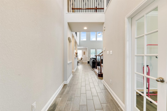 3413 Waverly Springs Ln, Pearland, TX 77581 - corridor with wood finished floors, baseboards, stairs, a high ceiling, and arched walkways
