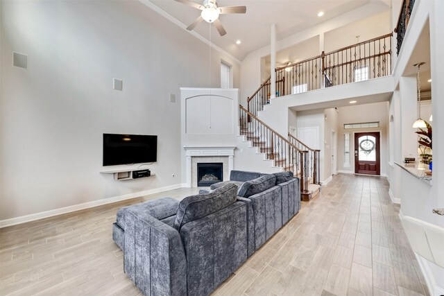 3413 Waverly Springs Ln, Pearland, TX 77581 - living area with a towering ceiling, stairs, a fireplace, a ceiling fan, and baseboards