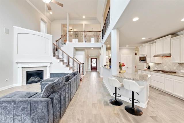 3413 Waverly Springs Ln, Pearland, TX 77581 - kitchen featuring a breakfast bar, open floor plan, light stone countertops, light wood-style floors, and tasteful backsplash