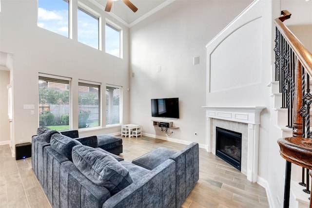 3413 Waverly Springs Ln, Pearland, TX 77581 - living area with a ceiling fan, a towering ceiling, light wood finished floors, ornamental molding, and a premium fireplace