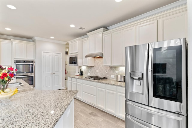 3413 Waverly Springs Ln, Pearland, TX 77581 - kitchen with appliances with stainless steel finishes, under cabinet range hood, ornamental molding, decorative backsplash, and recessed lighting