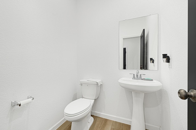 9506 Marble Park Ln, Baytown, TX 77521 - bathroom with baseboards, toilet, wood finished floors, and a sink