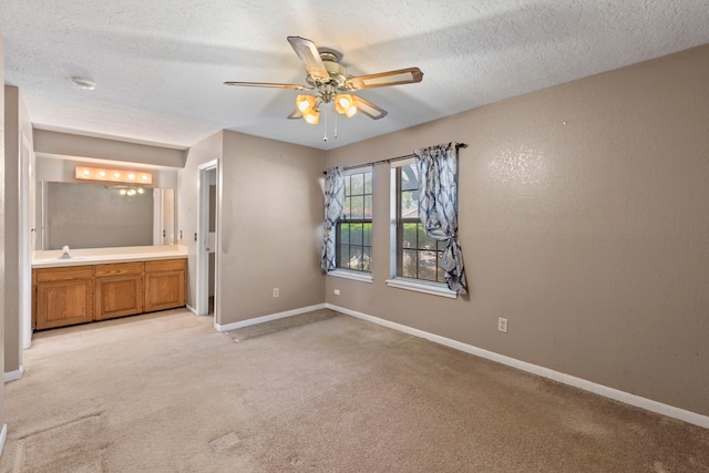 2413 38th Ave N, Texas City, TX 77590 - unfurnished bedroom featuring light carpet, baseboards, a sink, connected bathroom, and a textured ceiling