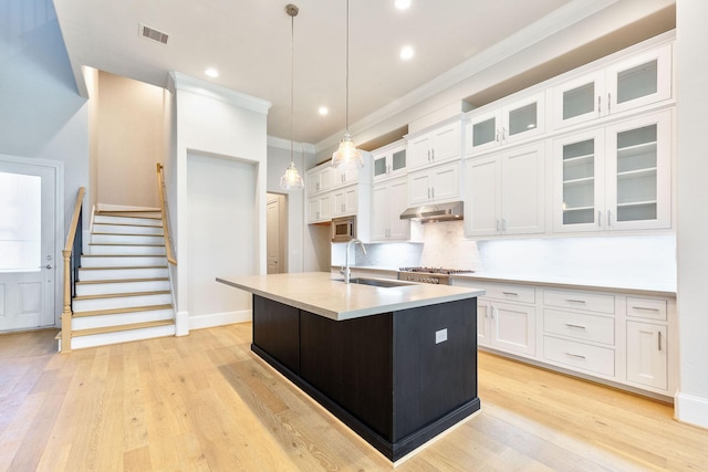 1008 Golden Nectar, Houston, TX 77008 - kitchen with a sink, white cabinets, stainless steel microwave, light wood-style flooring, and crown molding