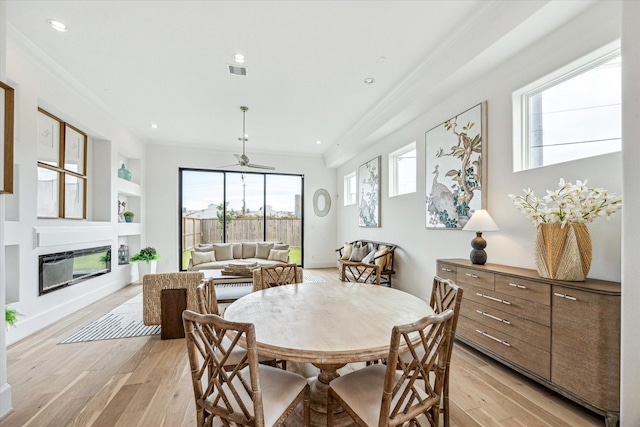 1008 Golden Nectar, Houston, TX 77008 - dining room with a glass covered fireplace, light wood finished floors, crown molding, built in shelves, and recessed lighting
