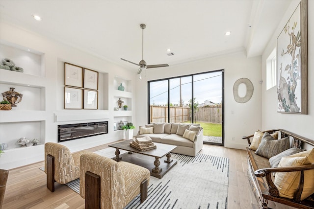 1008 Golden Nectar, Houston, TX 77008 - living room featuring built in features, light wood-style flooring, ornamental molding, ceiling fan, and a glass covered fireplace
