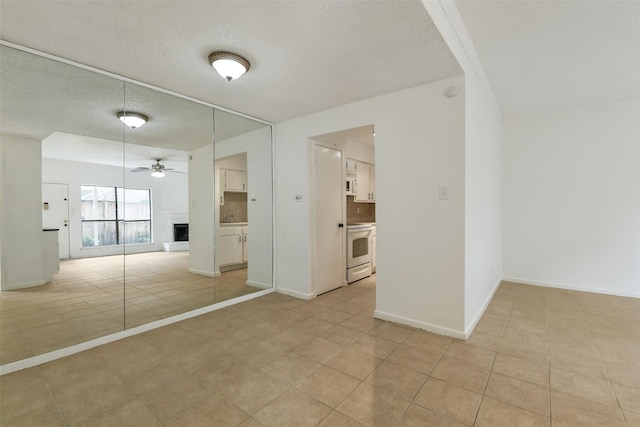 1100 Augusta Dr Unit 33, Houston, TX 77057 - unfurnished room featuring ceiling fan, a brick fireplace, light tile patterned floors, a textured ceiling, and baseboards