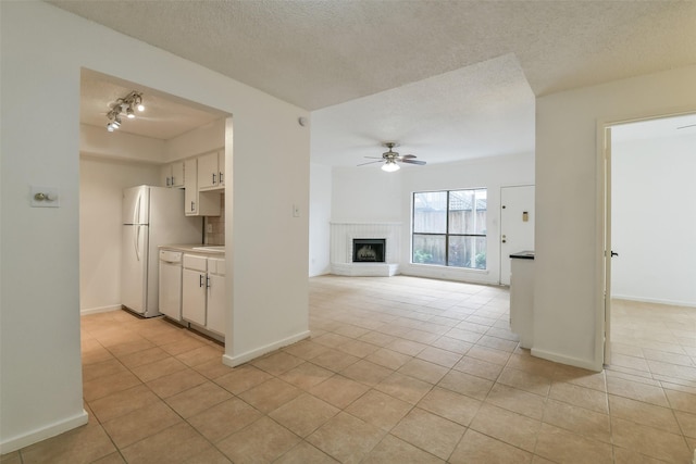 1100 Augusta Dr Unit 33, Houston, TX 77057 - unfurnished living room featuring light tile patterned floors, ceiling fan, a textured ceiling, a brick fireplace, and baseboards