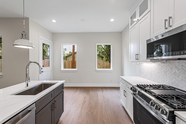 4224 Buck St, Houston, TX 77020 - kitchen with appliances with stainless steel finishes, a sink, light wood-style flooring, white cabinetry, and recessed lighting
