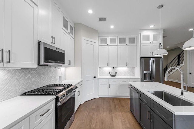 4224 Buck St, Houston, TX 77020 - kitchen with stainless steel appliances, a sink, wood finished floors, white cabinets, and recessed lighting