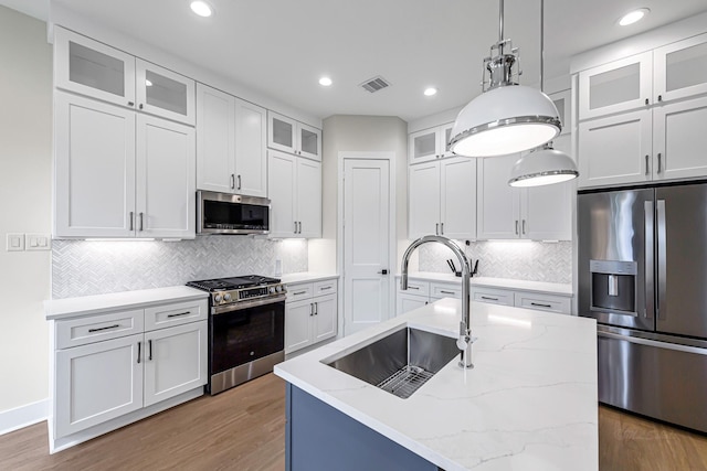4224 Buck St, Houston, TX 77020 - kitchen with appliances with stainless steel finishes, a sink, decorative backsplash, light wood finished floors, and white cabinets